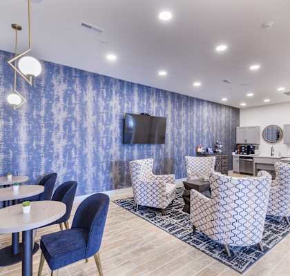 a communal area with chairs and tables and a television at Aventura at Wild Horse Creek, Chesterfield, 63017