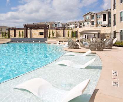 A pool with a white fountain in the middle of it.