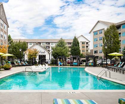 A large swimming pool surrounded by lounge chairs and umbrellas.