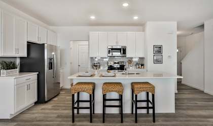 a kitchen with a large island with three stools at The Prairie Villas, Dardene Prairie Missouri