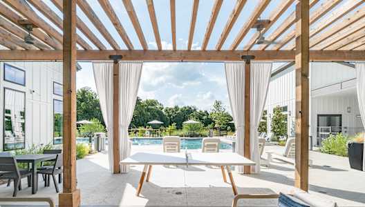 A wooden pergola over a patio with a table and chairs.