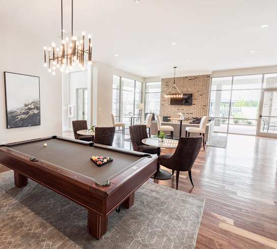 A pool table is in the middle of a room with a brick wall and a fireplace.