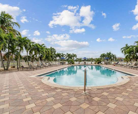 a swimming pool with palm trees and chairs around it at Bay Breeze Villas, Fort Myers, FL, 33908