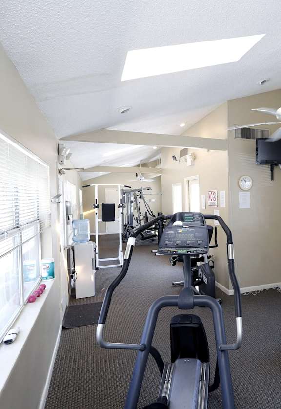 a gym with various machines and a ceiling fan