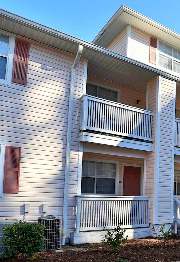 A two-story apartment building with a red door and a balcony.