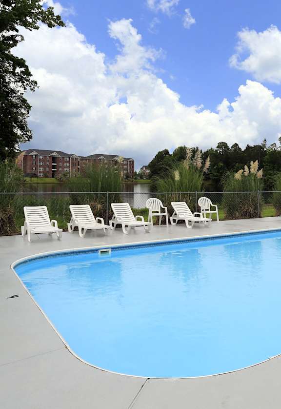 a swimming pool with chairs and a fence around it