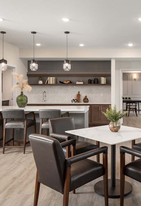 a dining area with a table and chairs and a kitchen with a large window