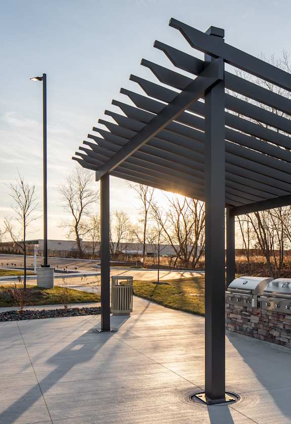 A pergola is in the middle of a walkway.