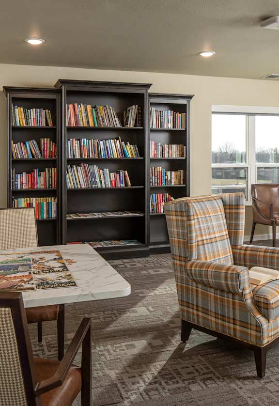 a living room with a table and chairs and a bookshelf filled with books