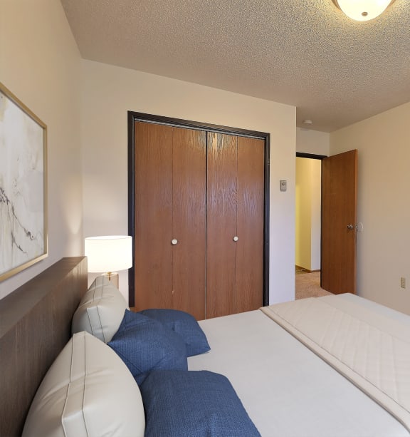 Fargo, ND Village West Apartments | Bedroom a blue building with a lawn and a fire hydrant in front of it