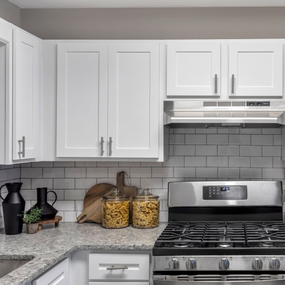 a white kitchen with stainless steel appliances and white cabinets at The Austin Apartment Homes, Deptford, 08096