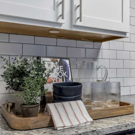 a kitchen counter with a tray with a book and plants on it at The Austin Apartment Homes, Deptford, 08096