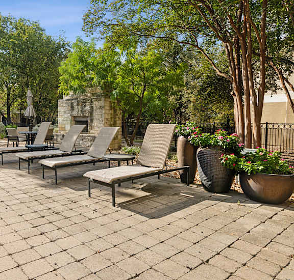 A patio with a pool and chairs.