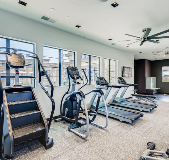 a gym with cardio equipment and windows in a building  at Grandstone at Sunrise, Peoria