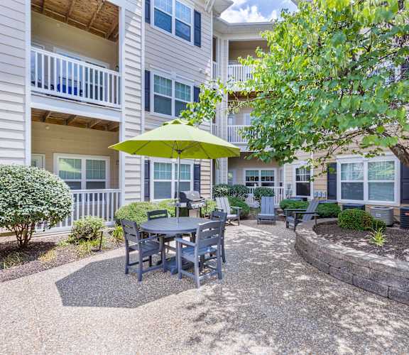 A patio with a table and chairs under a green umbrella.