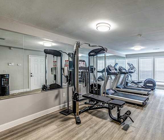 a gym with treadmills and other exercise equipment in a room with a mirror