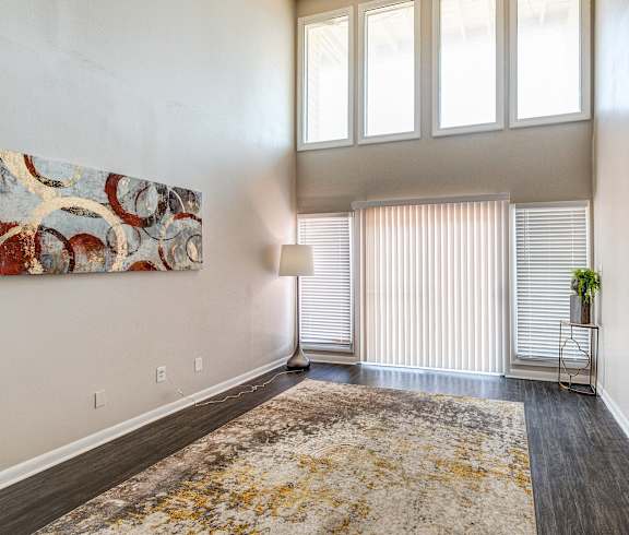 an empty living room with high ceilings and a window with blinds