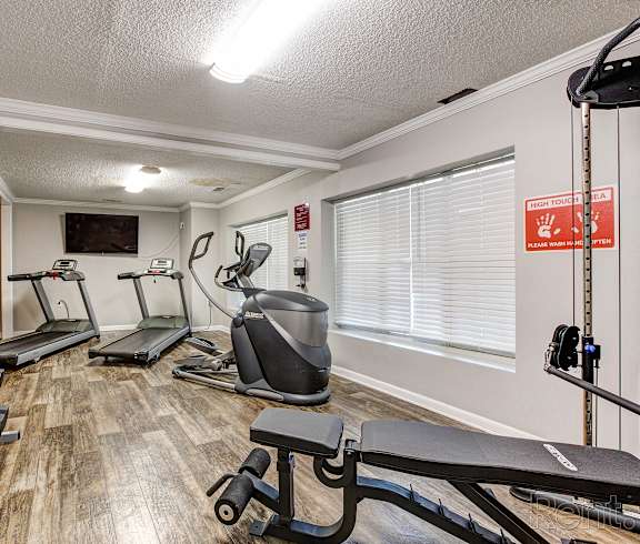 a gym with cardio machines and weights in a room with a window