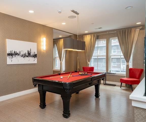 a game room with a pool table and red chairs