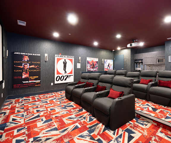 a home theater room with black couches and red pillows