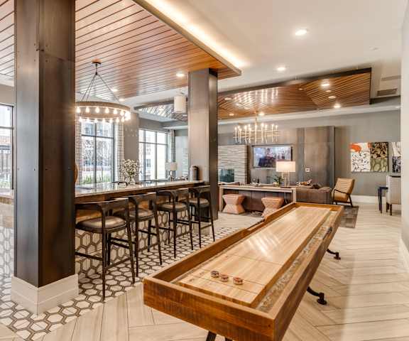 the lobby of a hotel with a bar and a communal table at Dartmoor Place at Oxford Square Apartments, Hanover, Maryland