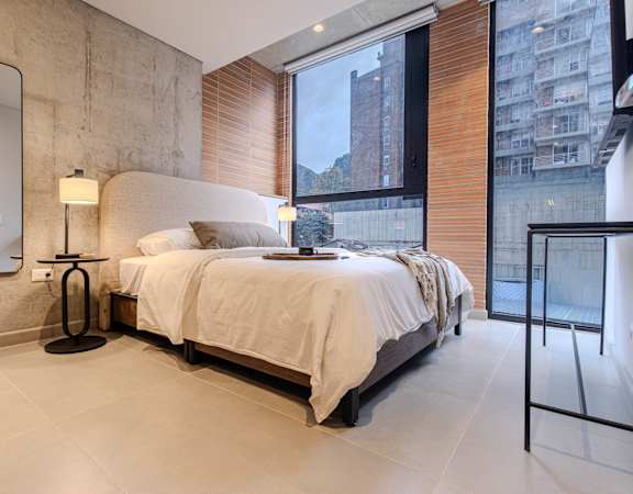 A bedroom with a large bed, a lamp, and a mirror on the wall.