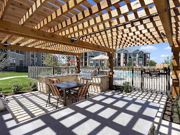 a patio with a table and chairs under a wooden pergola at North Creek, Hutto, 78634