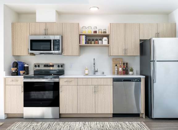 A modern kitchen with a refrigerator, oven, and microwave.
