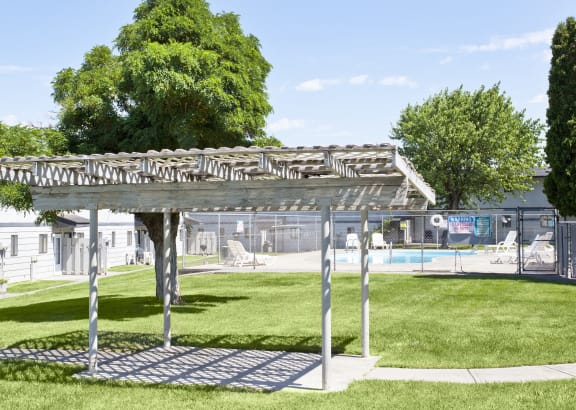 a pergola in a park next to a swimming pool