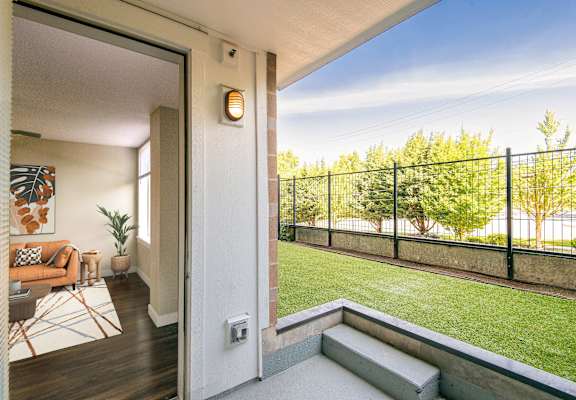 A balcony with a black railing and a small garden area.