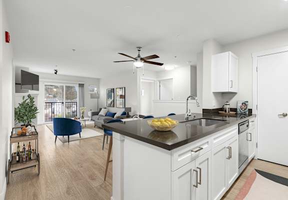 a kitchen and living room with white walls and wood flooring