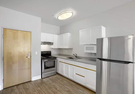 A kitchen with white cabinets and a stainless steel refrigerator.