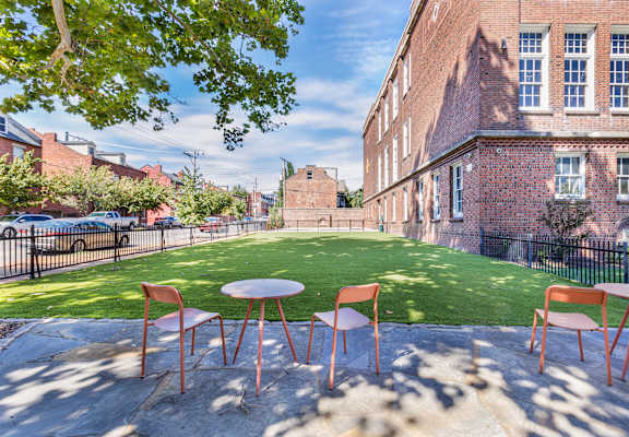 a courtyard with a table and chairs and a green lawn