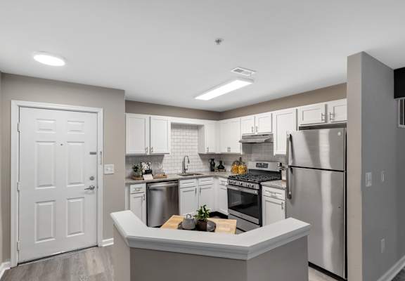 an open kitchen with stainless steel appliances and white cabinets at The Austin Apartment Homes, Deptford