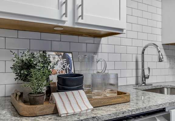 a kitchen counter with a tray with a book and plants on it at The Austin Apartment Homes, Deptford, NJ