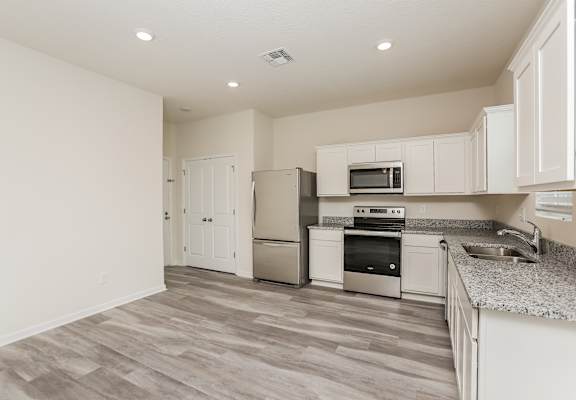 A kitchen with white cabinets and a grey floor.
