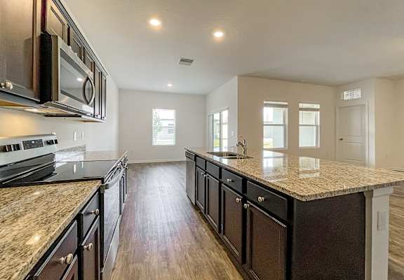 A kitchen with dark wood cabinets and granite countertops.