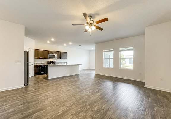 A spacious living room with a ceiling fan and hardwood flooring.