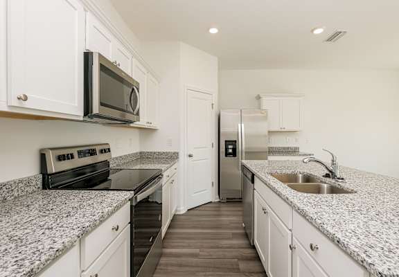 A kitchen with granite countertops and white cabinets.