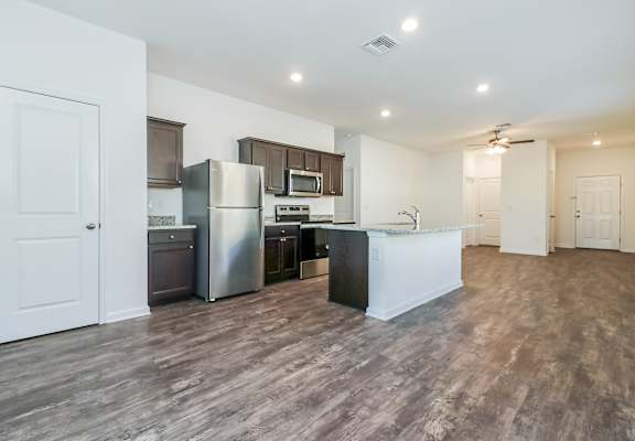 A kitchen with a refrigerator, microwave, and oven.