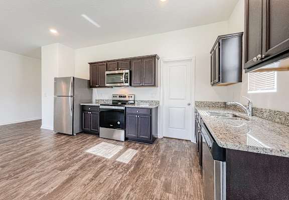 A kitchen with dark brown cabinets and a white door.