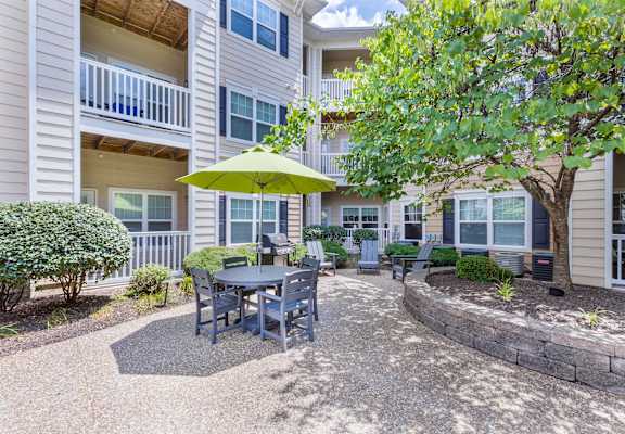 A patio with a table and chairs under a green umbrella.