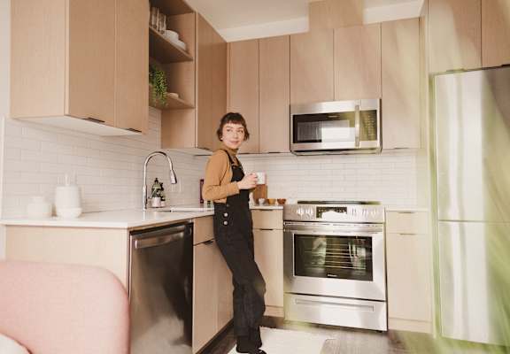 Woman Holding Coffee Cup Standing in Kitchen