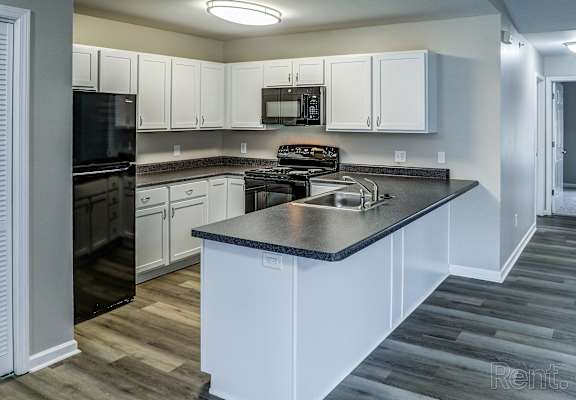 A kitchen with white cabinets and a black countertop.