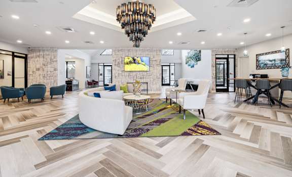 A spacious living room with a white sofa set and a chandelier.