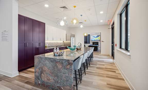 A kitchen with a marble island and purple cabinets.