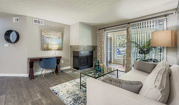 A living room with a couch, a chair, a table, a fireplace, and a painting on the wall.
