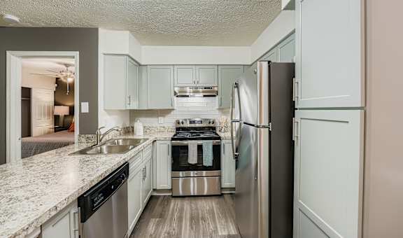 A kitchen with a refrigerator, sink, and stove.