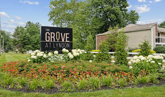 the grove apartments sign in front of flowers and plants