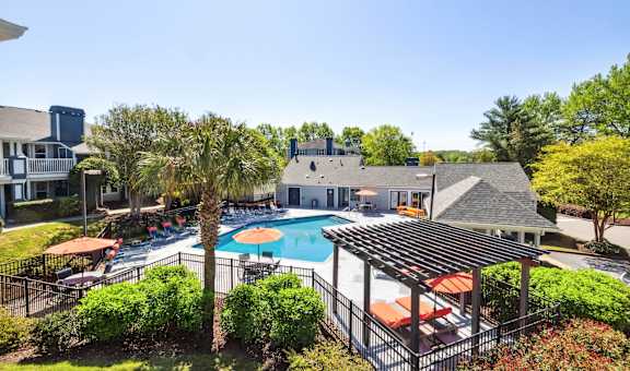 an aerial view of a pool with umbrellas and a building in the background
